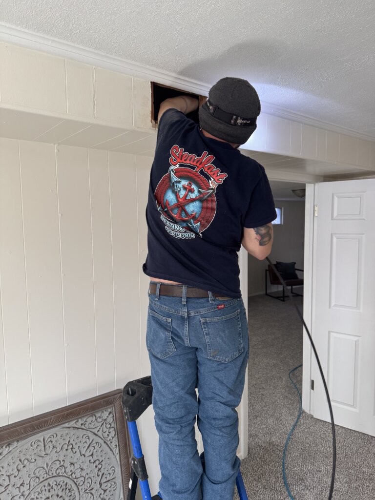 A picture of a guy working on a ceiling vent.