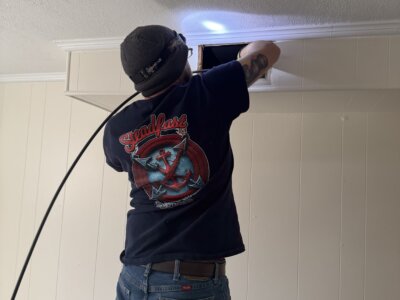 A picture of a guy working on a ceiling vent.