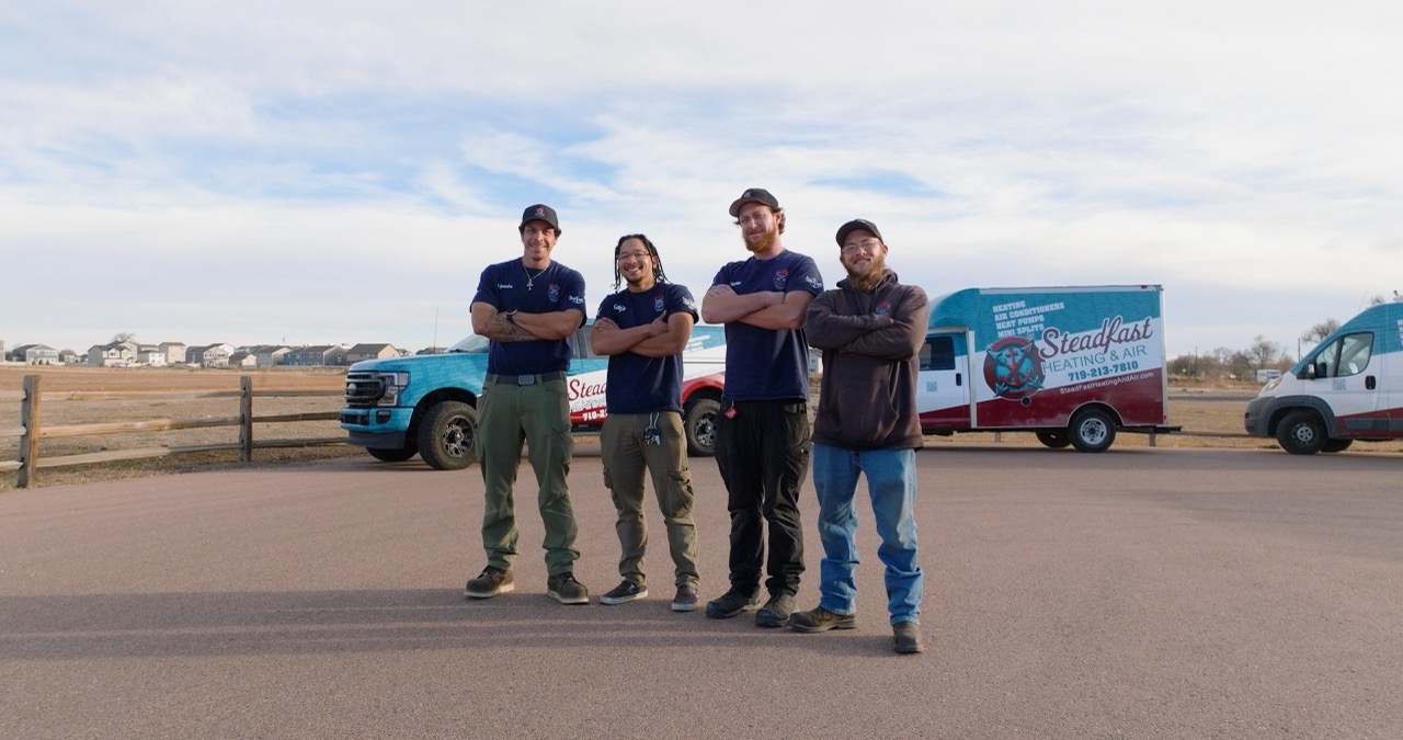 Steadfast Heating & Air team beside company service vehicles